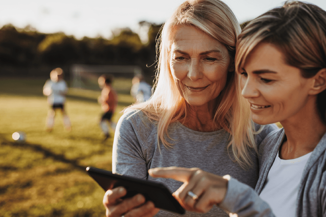 Two women looking at a tablet screen at soccer practice